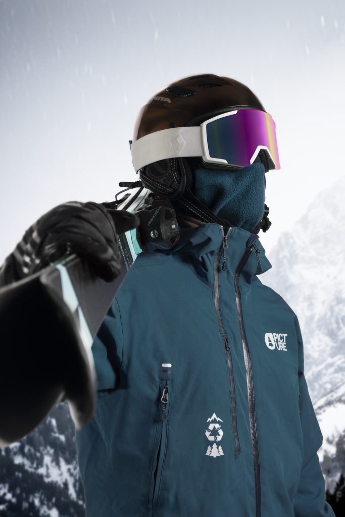 Portrait d'un skieur portant des ski sur son épaule avec des montagnes en fond